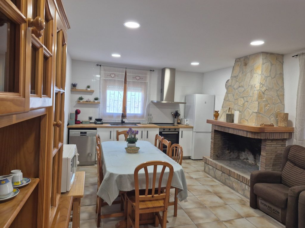 Cocina comedor con mesa para todo el grupo y chimenea en Casa DeltaNatura