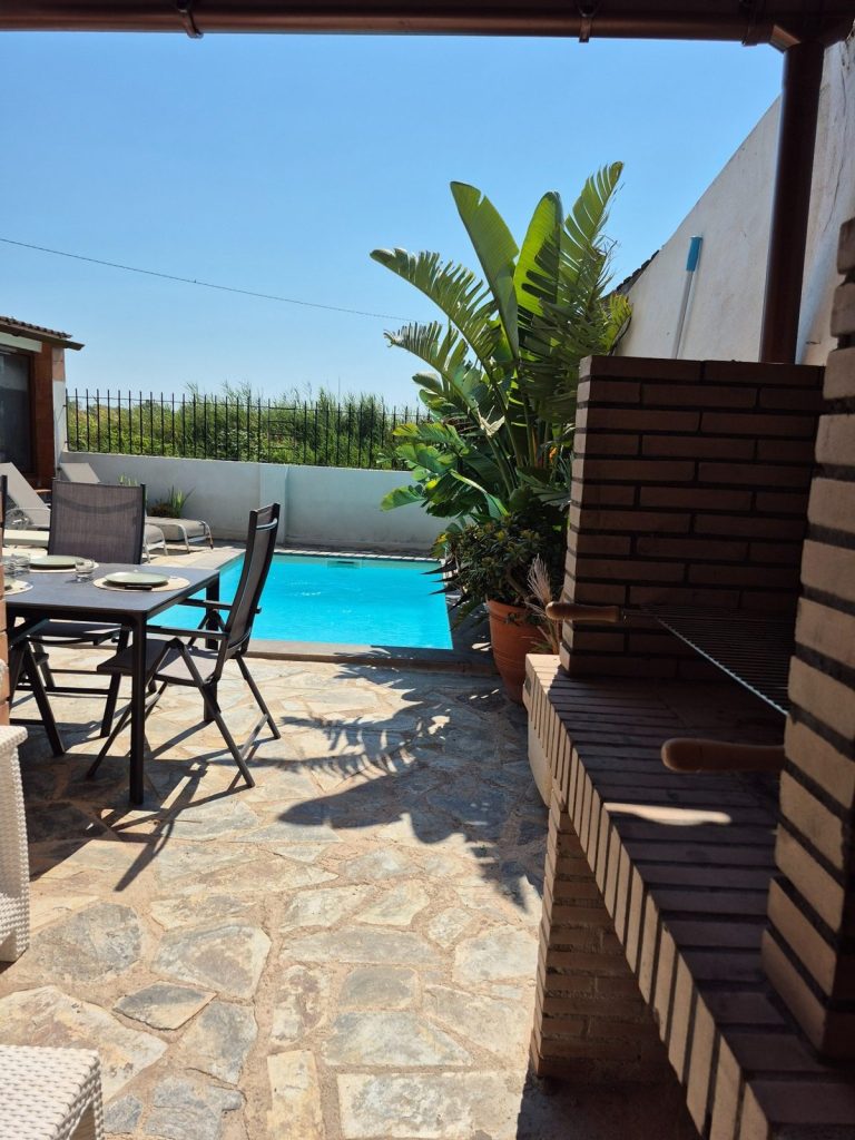 Barbacoa de obra y mesa exterior junto a la piscina salina privada de Casa DeltaNatura