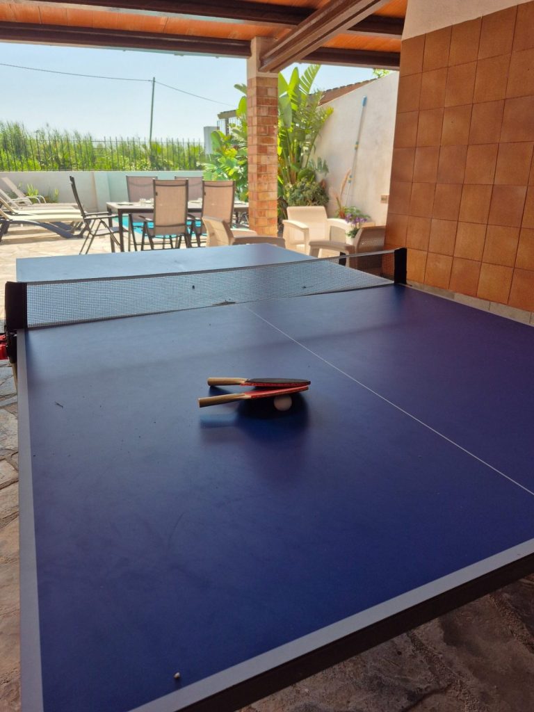 Mesa de ping-pong en el porche junto a la piscina y la mesa exterior de Casa DeltaNatura